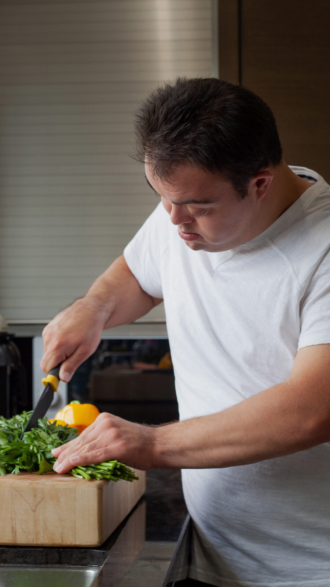 Man focused on chopping vegetables in a kitchen.